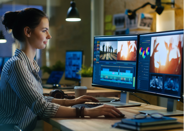 A person edits a video on their monitors
